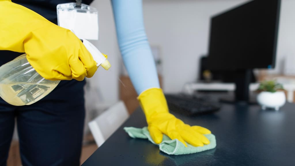Profesional limpiando una superficie de oficina para mantenimiento recurrente en Valencia